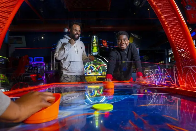 Friends play air hockey in Q-ZAR&rsquo;s arcade